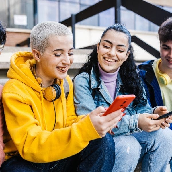 Group of multiracial teenage students using mobile phones on school Young friends watching social media content on smartphones