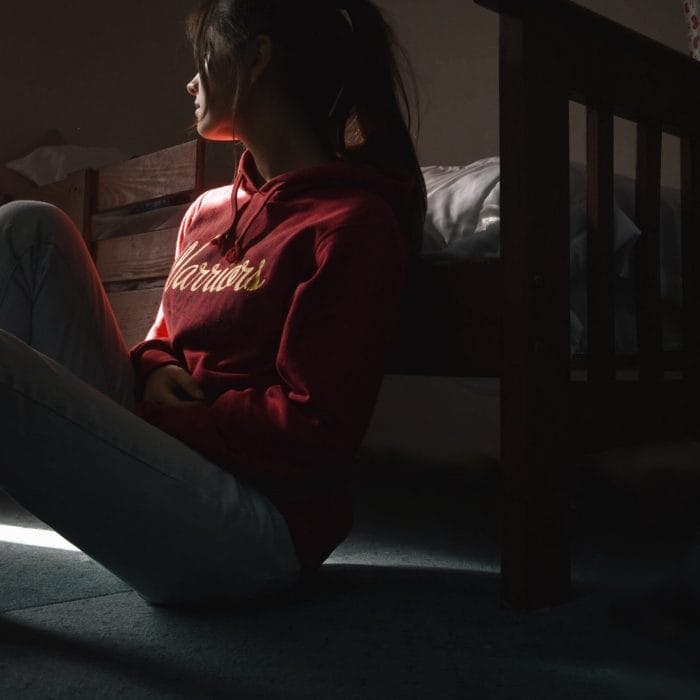Teen sitting on floor in the dark
