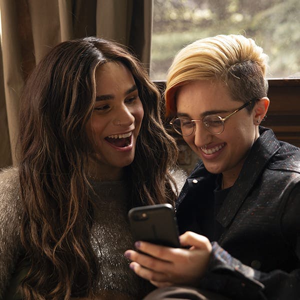Transgender teens looking at mobile phone together, happily.