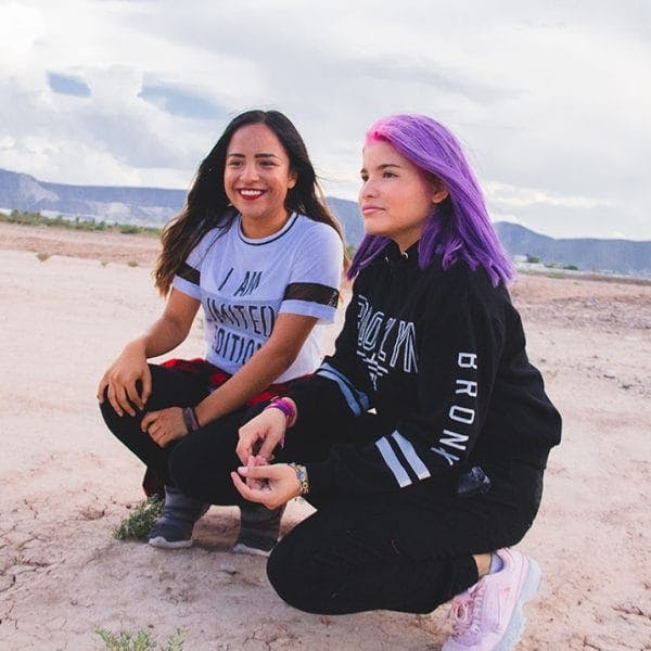 Two teens kneeling in desert
