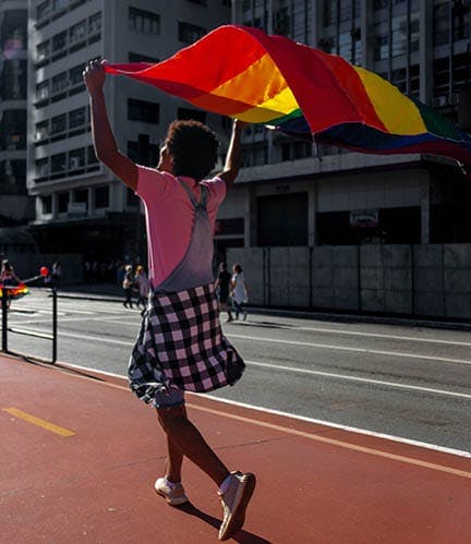 Teen holding a pride flag over their head.