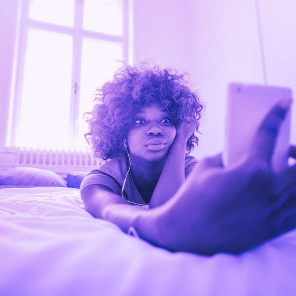 teen looking at phone on bed