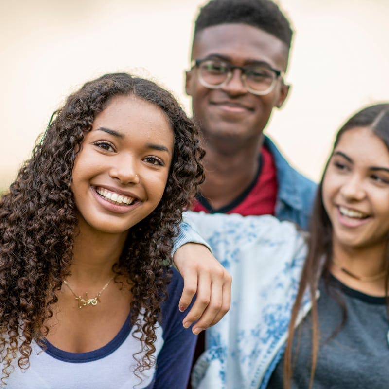 group of three teens smile at camera