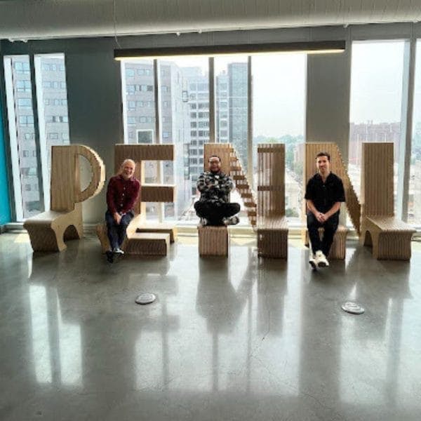 three people sit in front of large letters spelling P-E-N-N