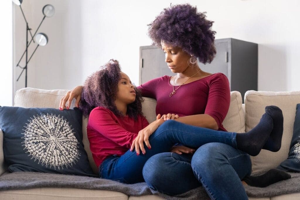 a mother and daughter sitting together on the couch