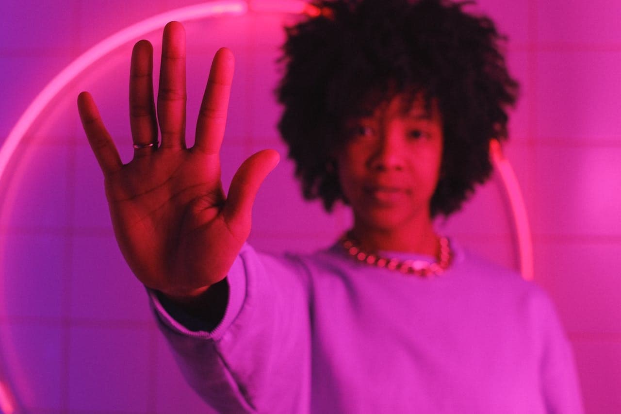 woman standing with raised arm in room with pink illumination