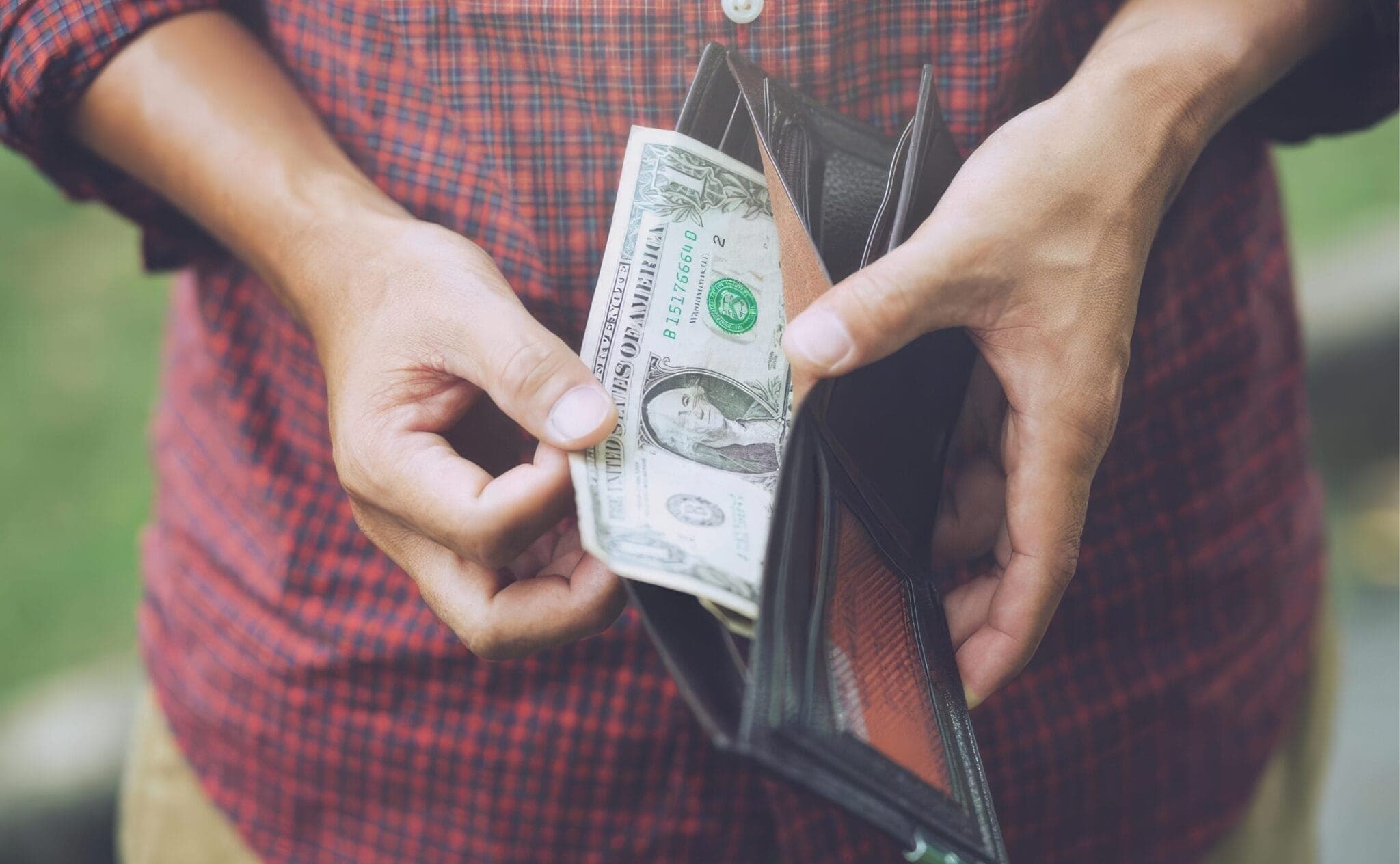 person pulling a dollar bill out of a wallet
